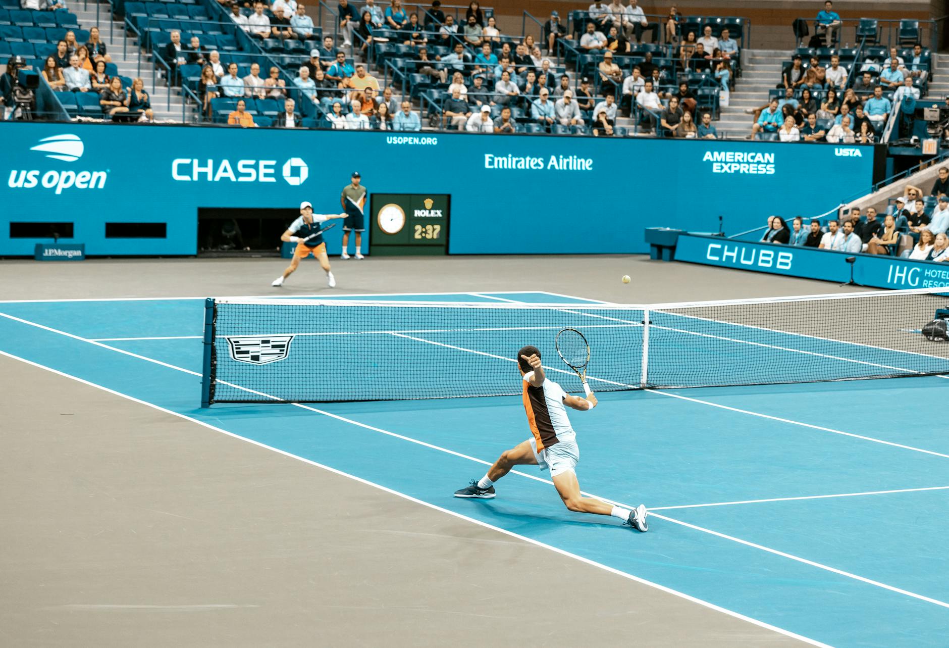 Dynamic scene of players in action at the US Open on a bright tennis court.