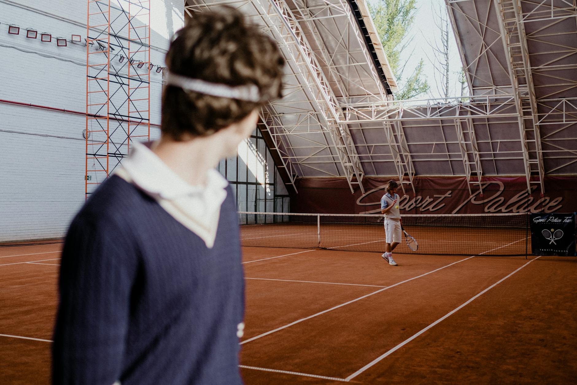 Tennis players on an indoor clay court during a competitive match.