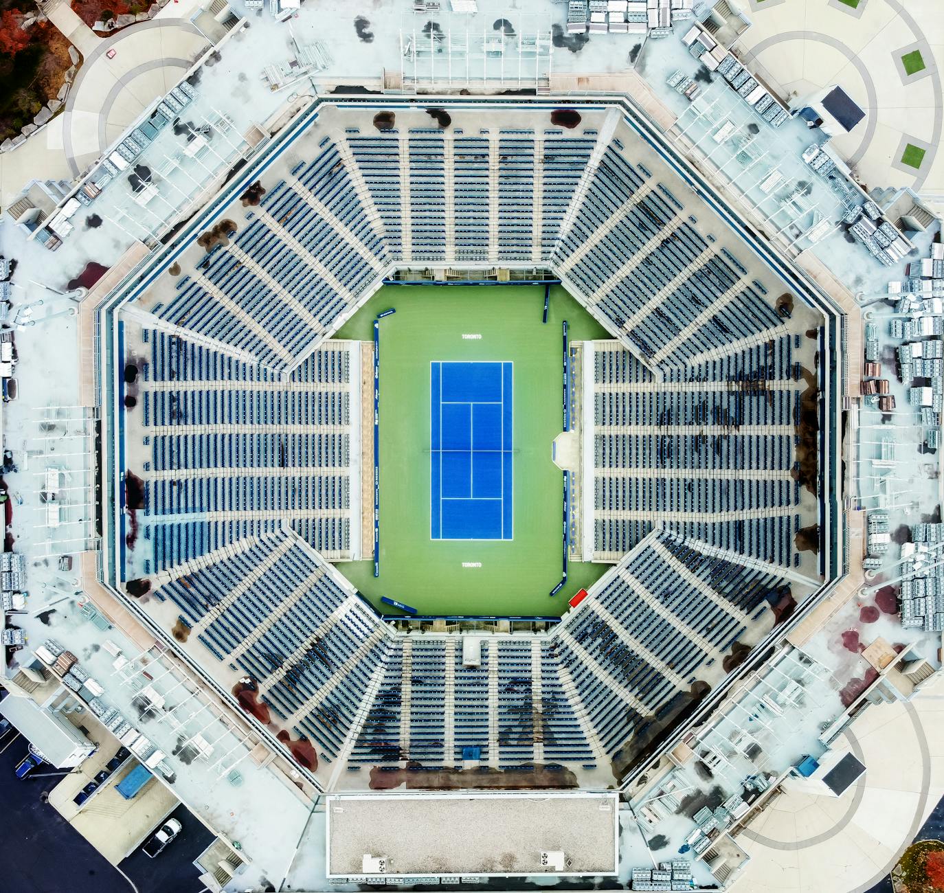 Stunning aerial view of a large, empty tennis stadium with a blue court at the center.