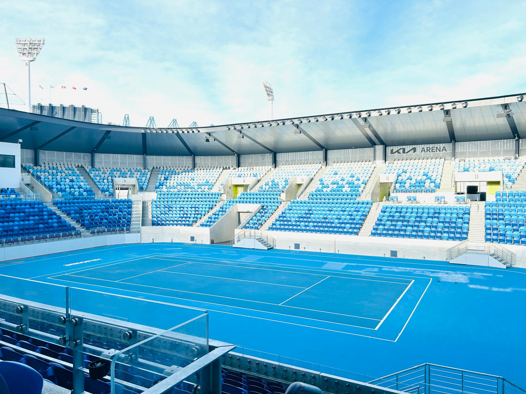 An empty blue tennis court at Melbourne's Kia Arena during daytime.