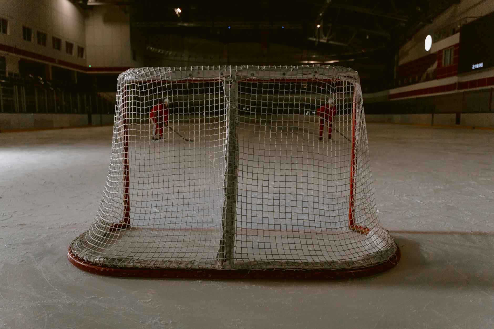 Intense hockey game in an indoor rink with focus on the goalpost.