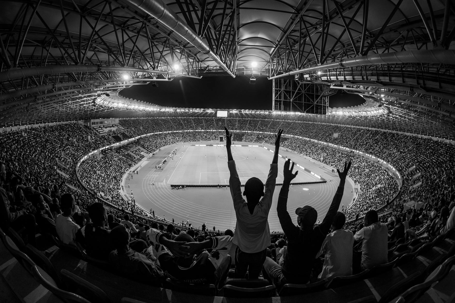 Black and white photo of a lively sports event at Kigali City Stadium, Rwanda.