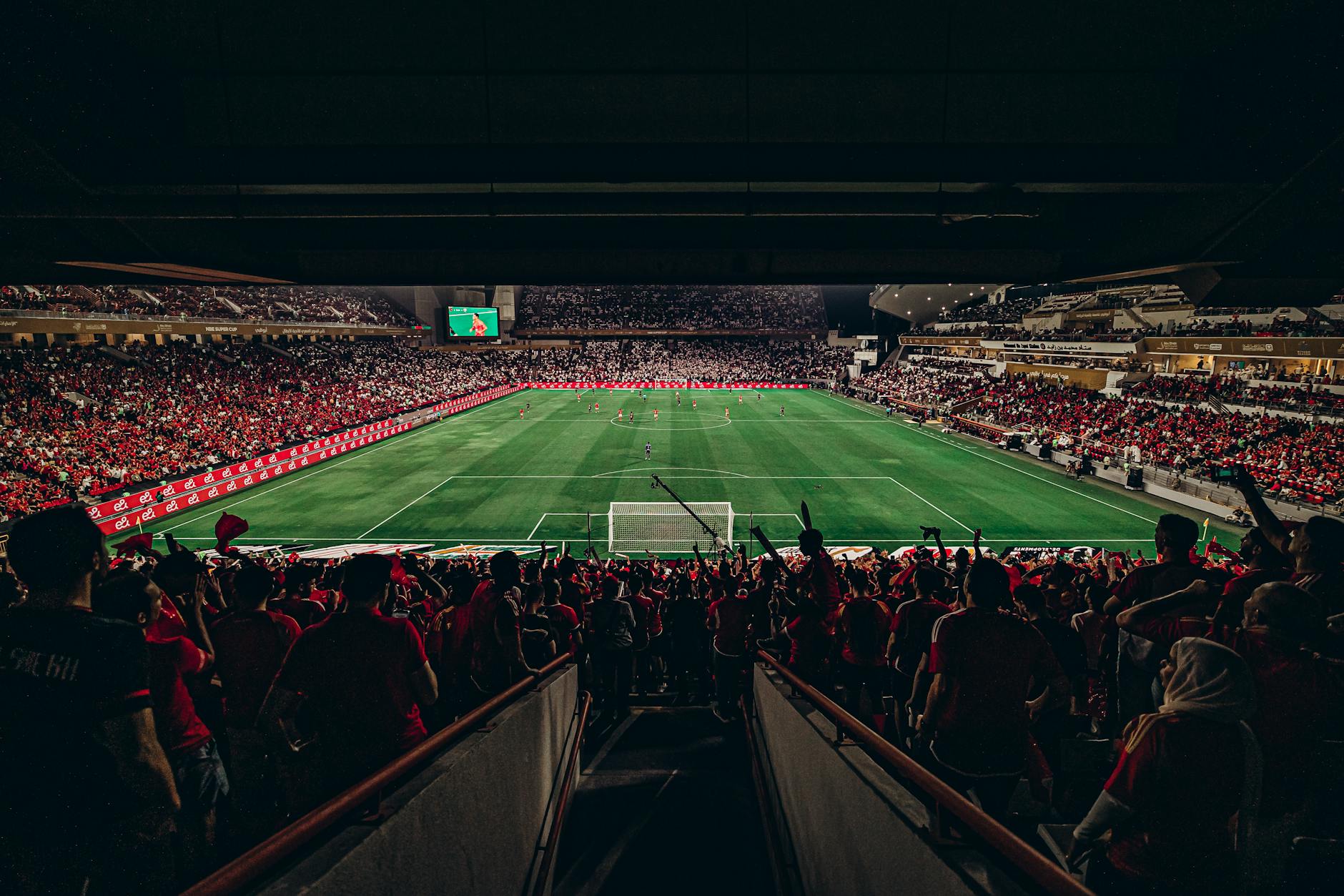 An exciting football match with passionate fans filling the stadium under bright lights, capturing sports energy.