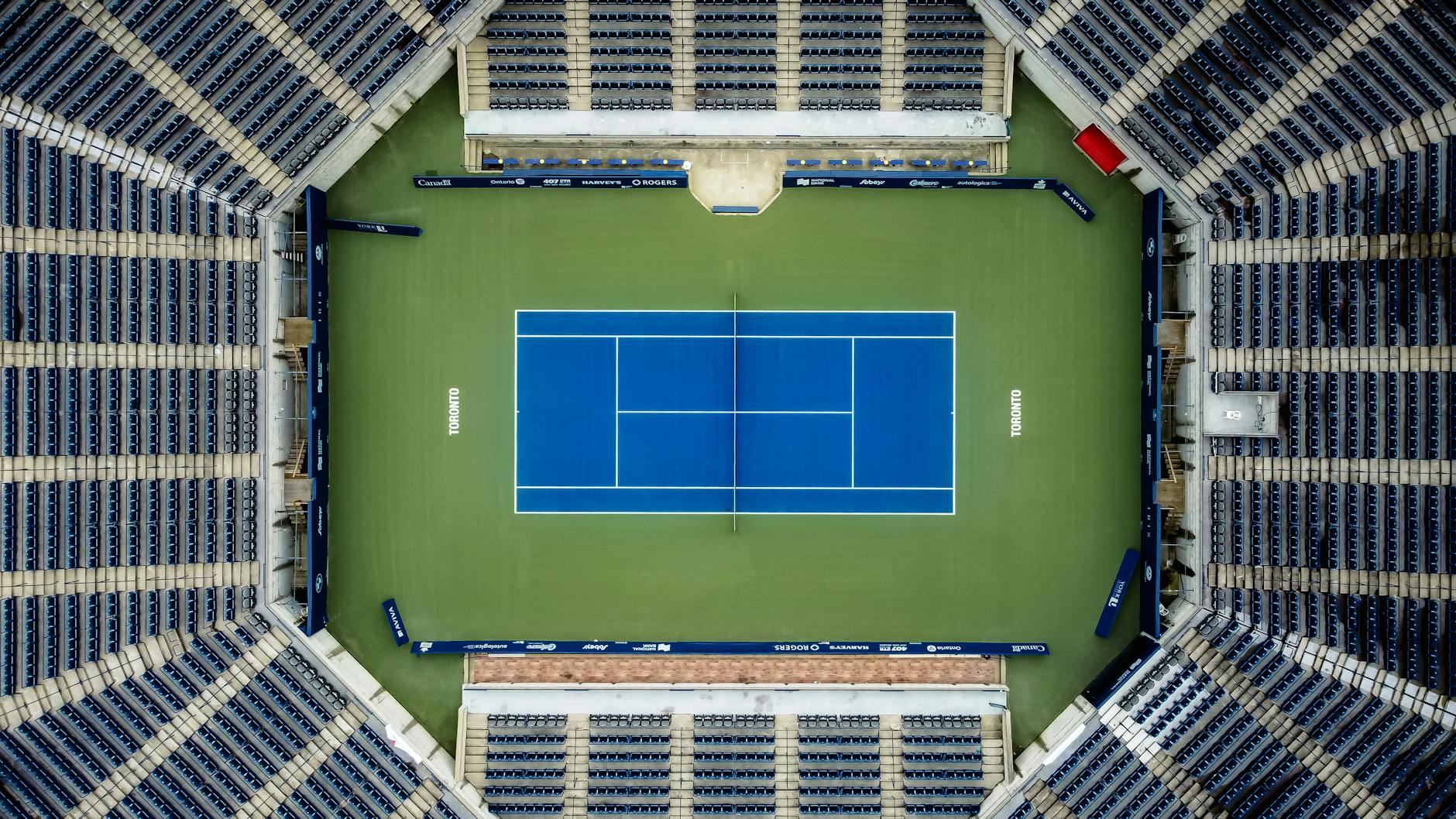Top-down view of an empty tennis court in a stadium, perfect for sports-themed projects.