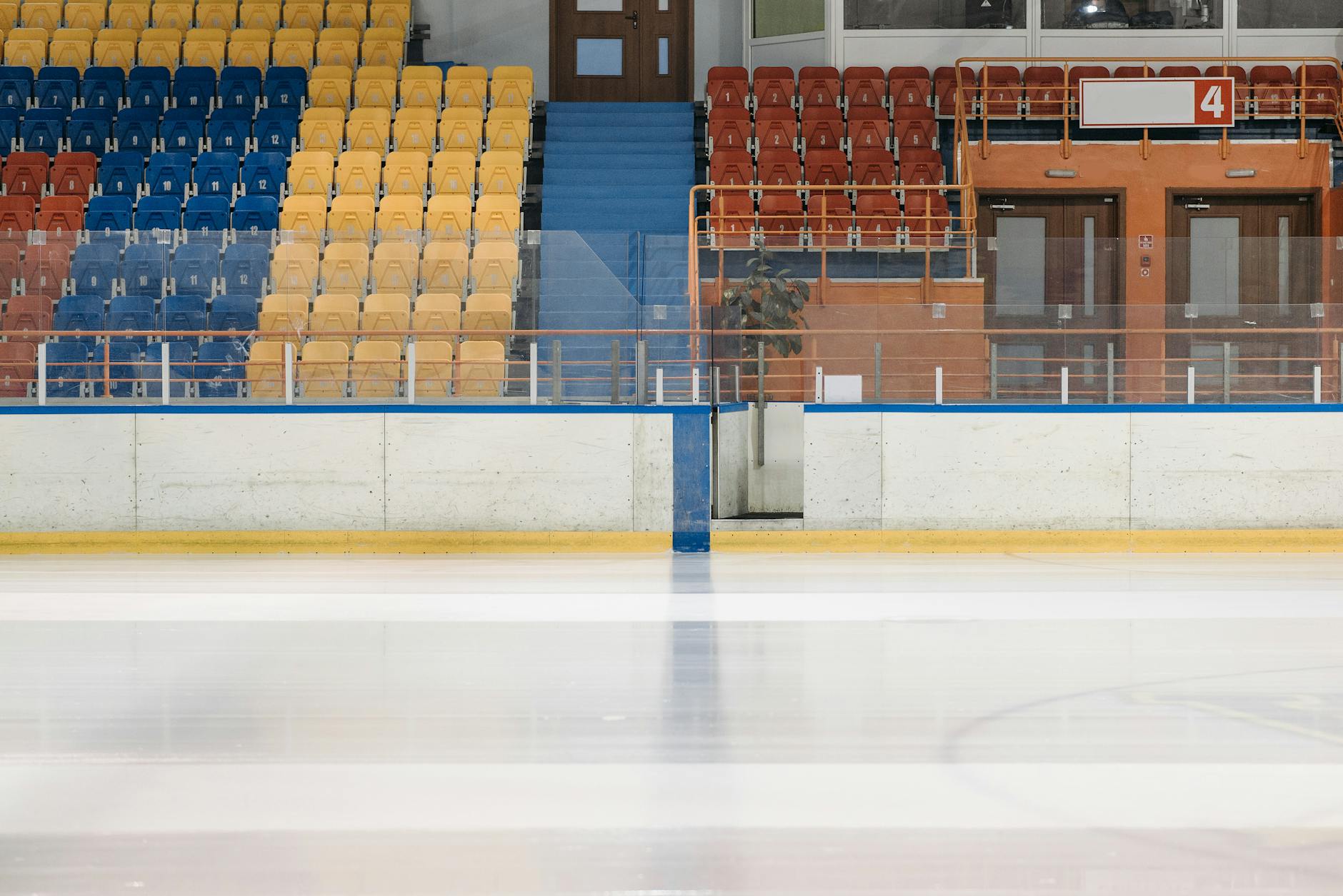 Empty ice rink showcasing colorful bleachers with a modern sports venue design.