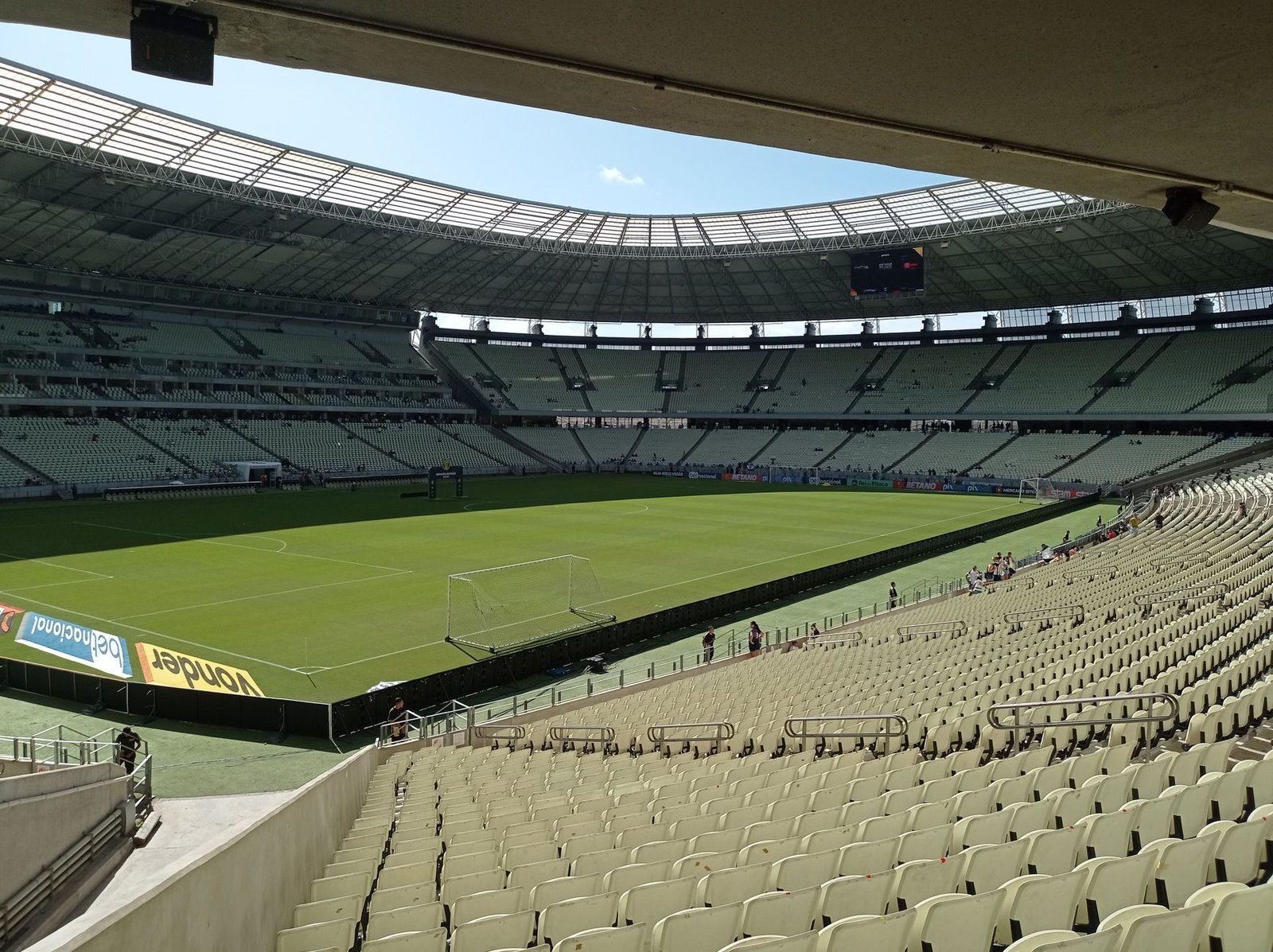 A wide view of an empty stadium under bright daylight, capturing the essence of calm before the excitement of a sports event.